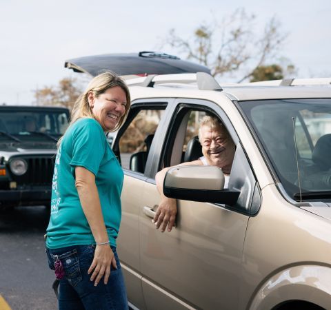 A woman greeting people inside of a car.